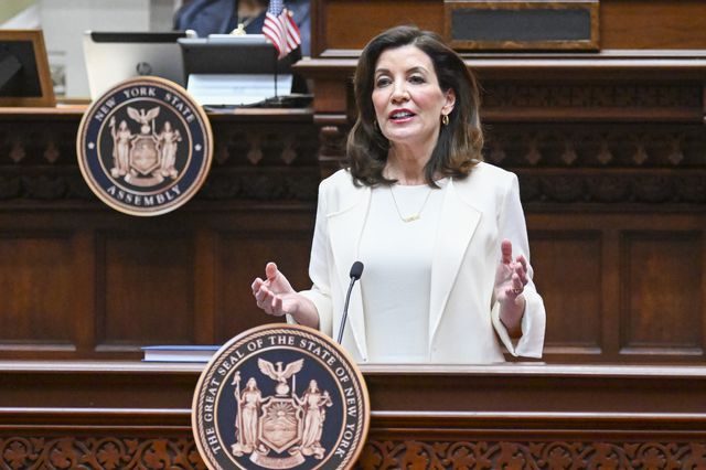 Governor Kathy Hochul, wearing a white dress, delivers her first State of the State address.